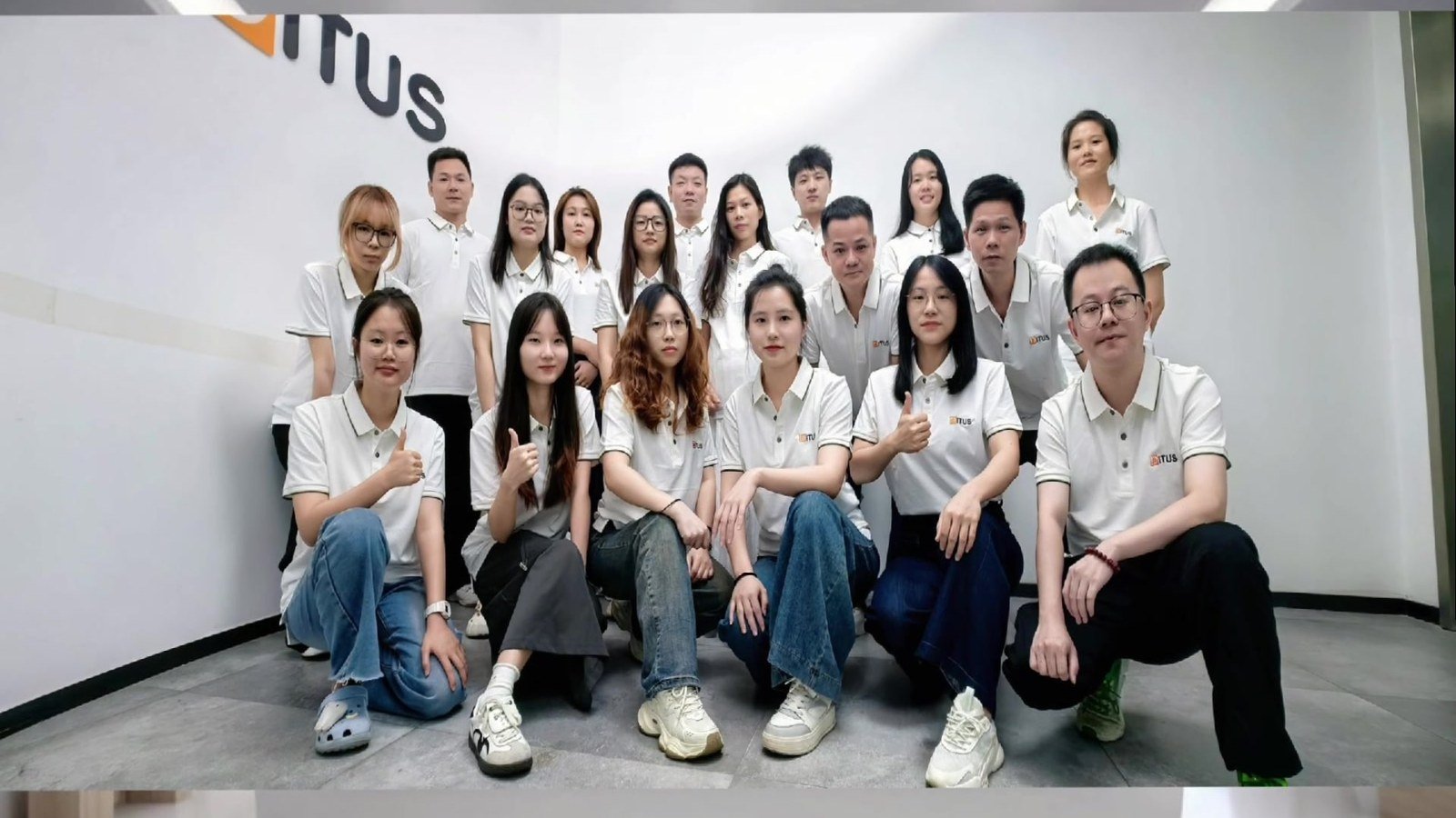 The full Bitus team posing in front of the Bitus logo wall